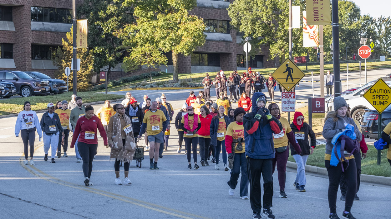 UMSL 5K partipants make their way down Grobman Drive with Woods Hall in the background 